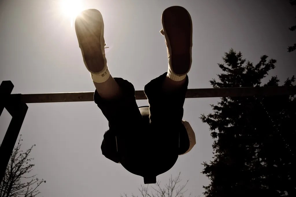 A child on a swing seen from the bottom with the sun in the background